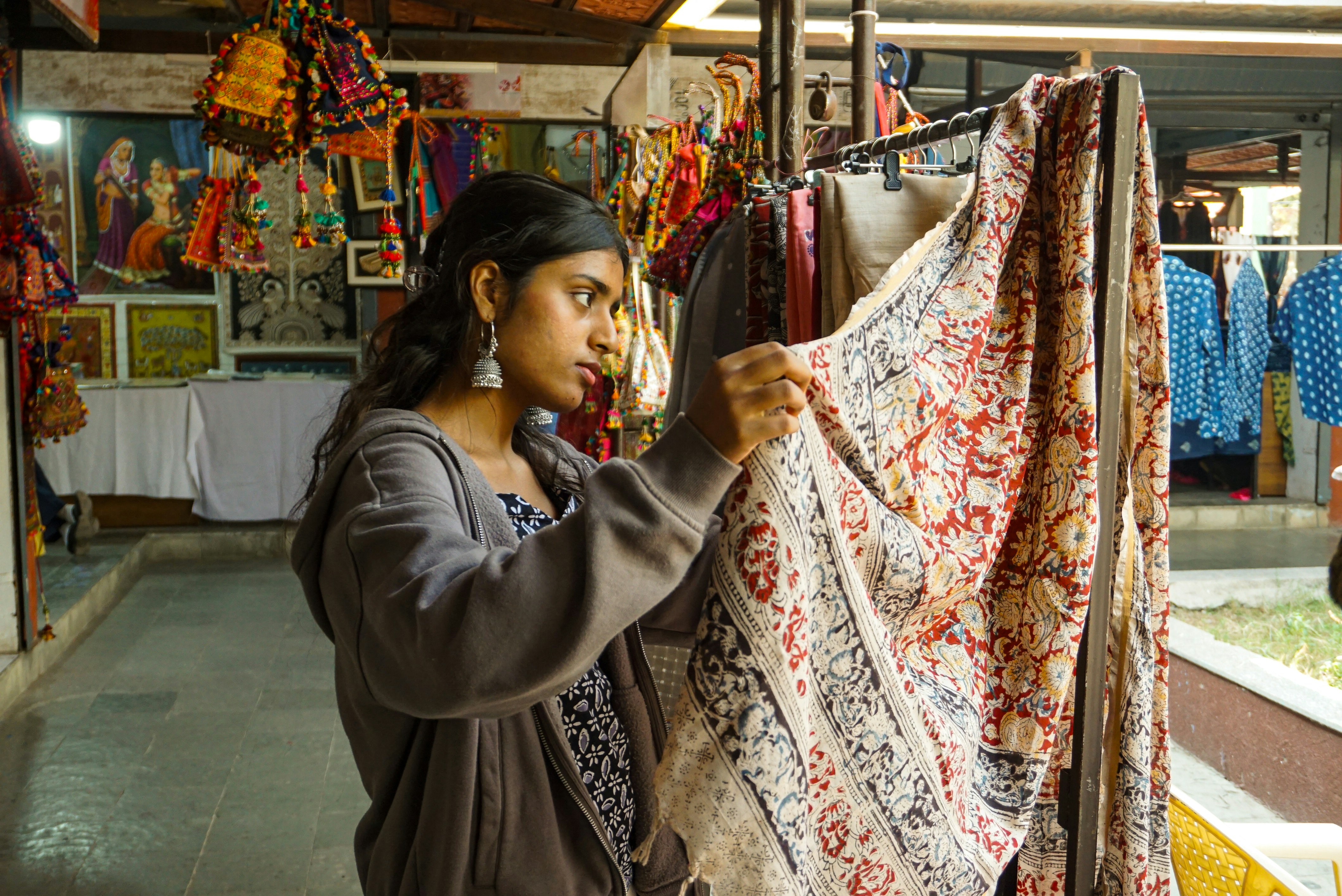 Woman examining fabric at a busy outdoor textile market, representing the vibrant wholesale clothing supplier scene in Guangzhou