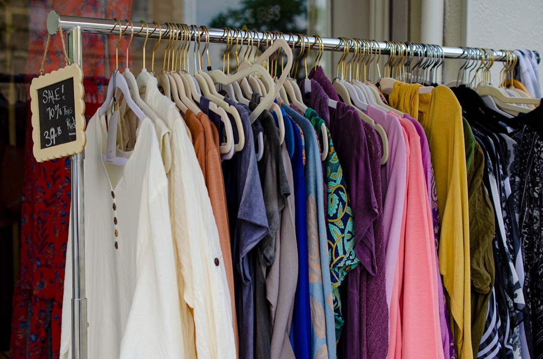 A rack of second hand clothing in a thrift store, showcasing assorted shirts and casual wear available for wholesale purchase
