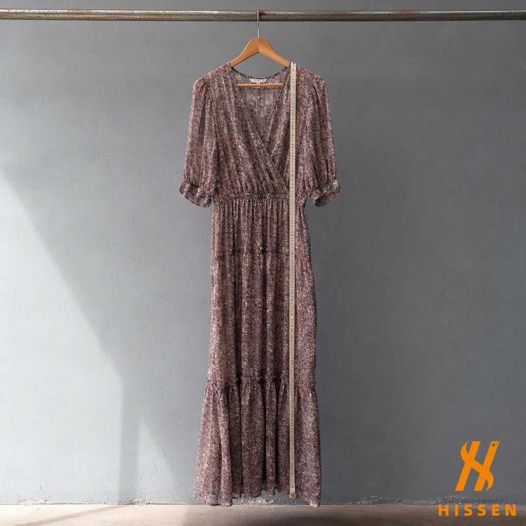 A used long dress on a wooden hanger with a cloth tape measure running from the shoulder seam to the hem