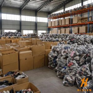 Used shoe bales stacked on industrial shelving in a wholesale export warehouse